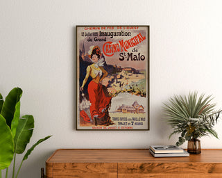 Vintage poster Bretagne – Saint-Malo, opening van het casino, ingelijst boven een houten ladekast, tussen planten.