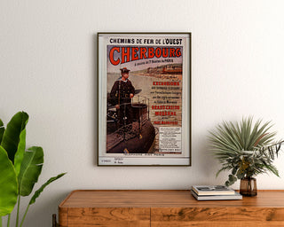 Vintage Normandië-poster – Cherbourg, chemins de fer de l’Ouest, ingelijst boven een houten dressoir tussen planten.