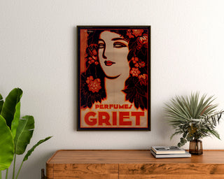 Vintage advertising poster Perfumes Griet, framed above a wooden dresser between plants.