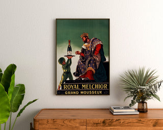 Vintage reclameposter Royal Melchior, grand mousseux, ingelijst boven een houten dressoir, tussen planten.