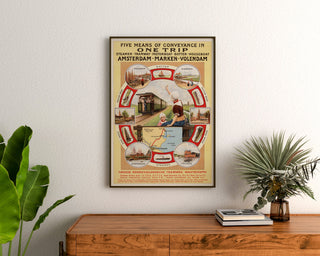 Vintage toeristenposter – Amsterdam, Marken en Volendam, ingelijst boven een houten dressoir tussen planten.