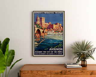 Vintage reisposter – Avignon, Romaans & Middeleeuws Frankrijk, ingelijst boven een houten dressoir, tussen planten.