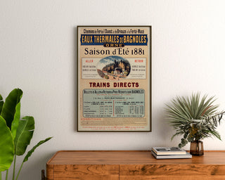 Vintage reisposter – Bagnoles, thermale wateren, ingelijst boven een houten dressoir, tussen planten.