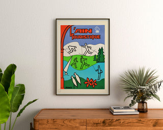 Vintage toeristische affiche – L’Ain touristique, ingelijst boven een houten dressoir, tussen planten.