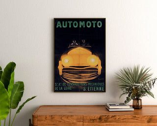 Vintage poster Automoto, Saint-Étienne, ingelijst boven een houten ladekast, tussen planten.