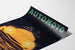 Vintage poster Automoto, Saint-Étienne, gepresenteerd op een gebogen vel, schuin gefotografeerd.