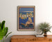 Vintageposter Cannes, Les Sports Élégants, ingelijst boven een houten dressoir tussen planten.