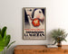Vintage affiche Exposition Achille Mauzan, ingelijst boven een houten dressoir, tussen planten.