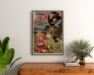 Vintageposter Laiterie de l’Isle Briant, Angers, ingelijst boven een houten dressoir tussen planten.