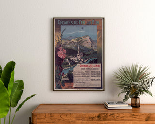 Vintage poster Lourdes, badplaatsen, ingekaderd boven een houten dressoir, tussen planten.