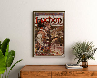 Vintage poster Luchon, la reine des Pyrénées, ingelijst boven een houten dressoir, tussen planten.