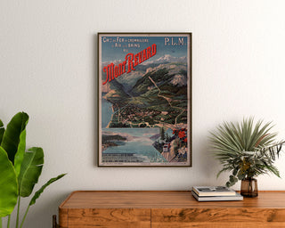 Vintageposter Mont-Revard, tandradspoor, ingelijst boven een houten dressoir tussen planten.