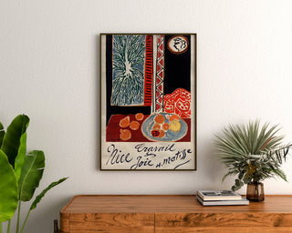 Vintageposter Nice, Travail et Joie, ingelijst boven een houten dressoir tussen planten.
