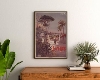 Vintage P.L.M. Hyères poster, framed above a wooden dresser, between plants.