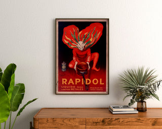 Vintage poster Rapidol, ingelijst boven een houten dressoir, tussen planten.