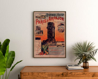 Vintage poster Tramway Paris–Arpajon, ingelijst boven een houten dressoir, tussen planten.
